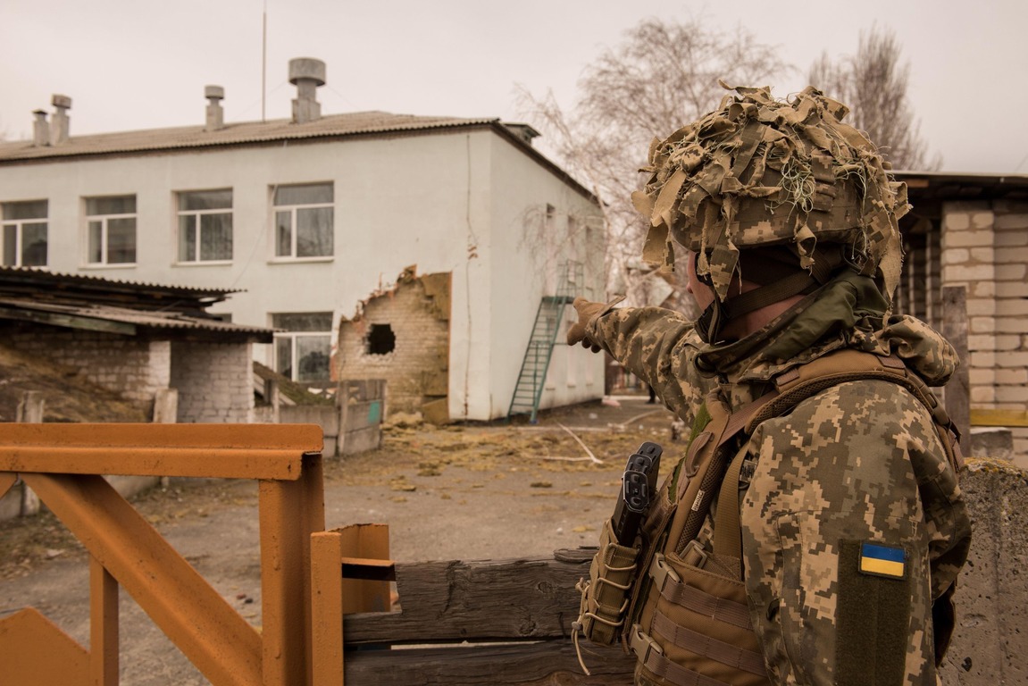 Ukrainian soldier points towards a building in the east of the country