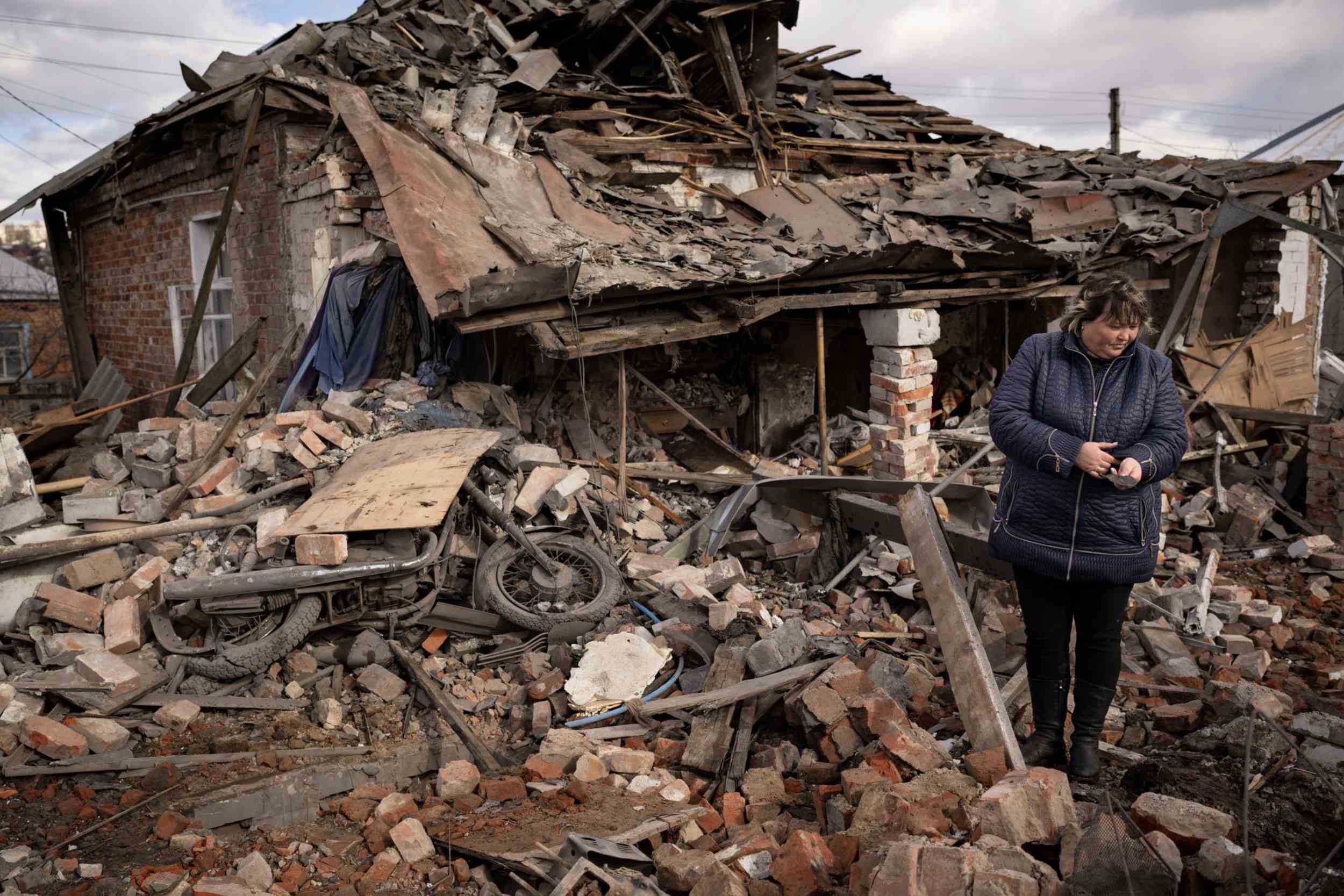 жінка біля зруйнованого будинку