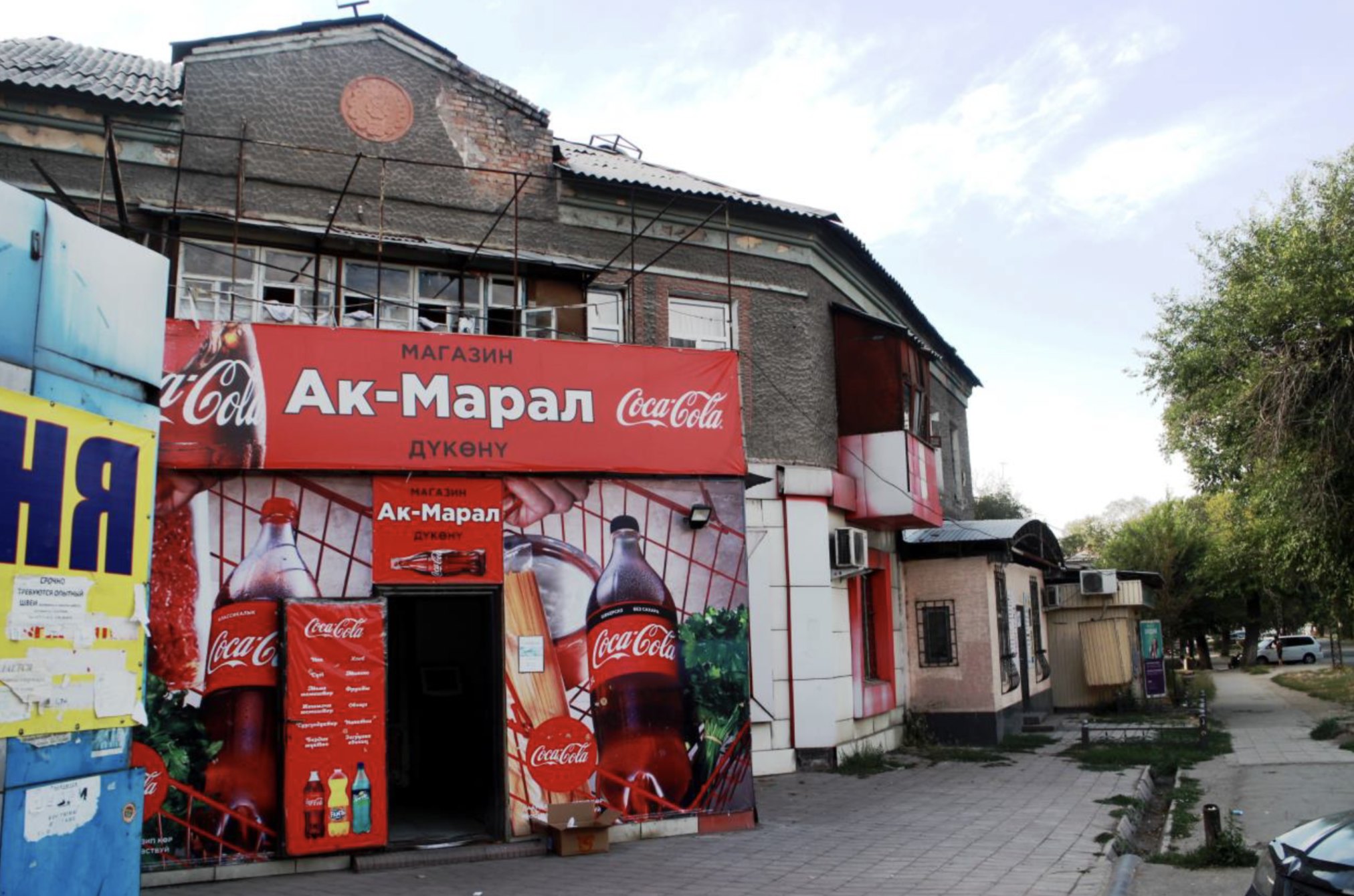 Магазин «Ак-Марал» перед двоповерховим будинком, побудованим Інтергельпо